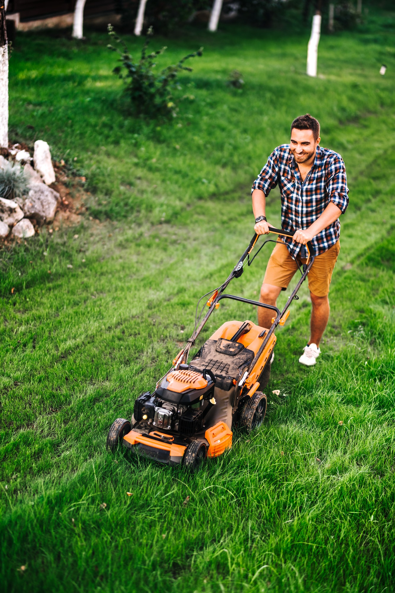 industrial gardener working with lawnmower and cutting grass in garden